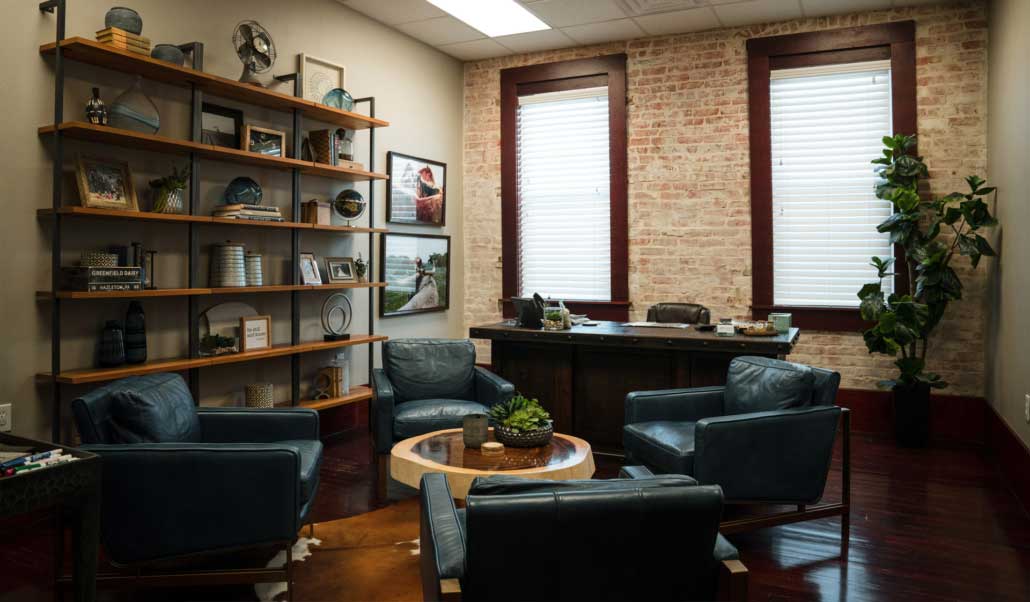 A leather-furnished lounge with open shelving and exposed brick at the Heritage office